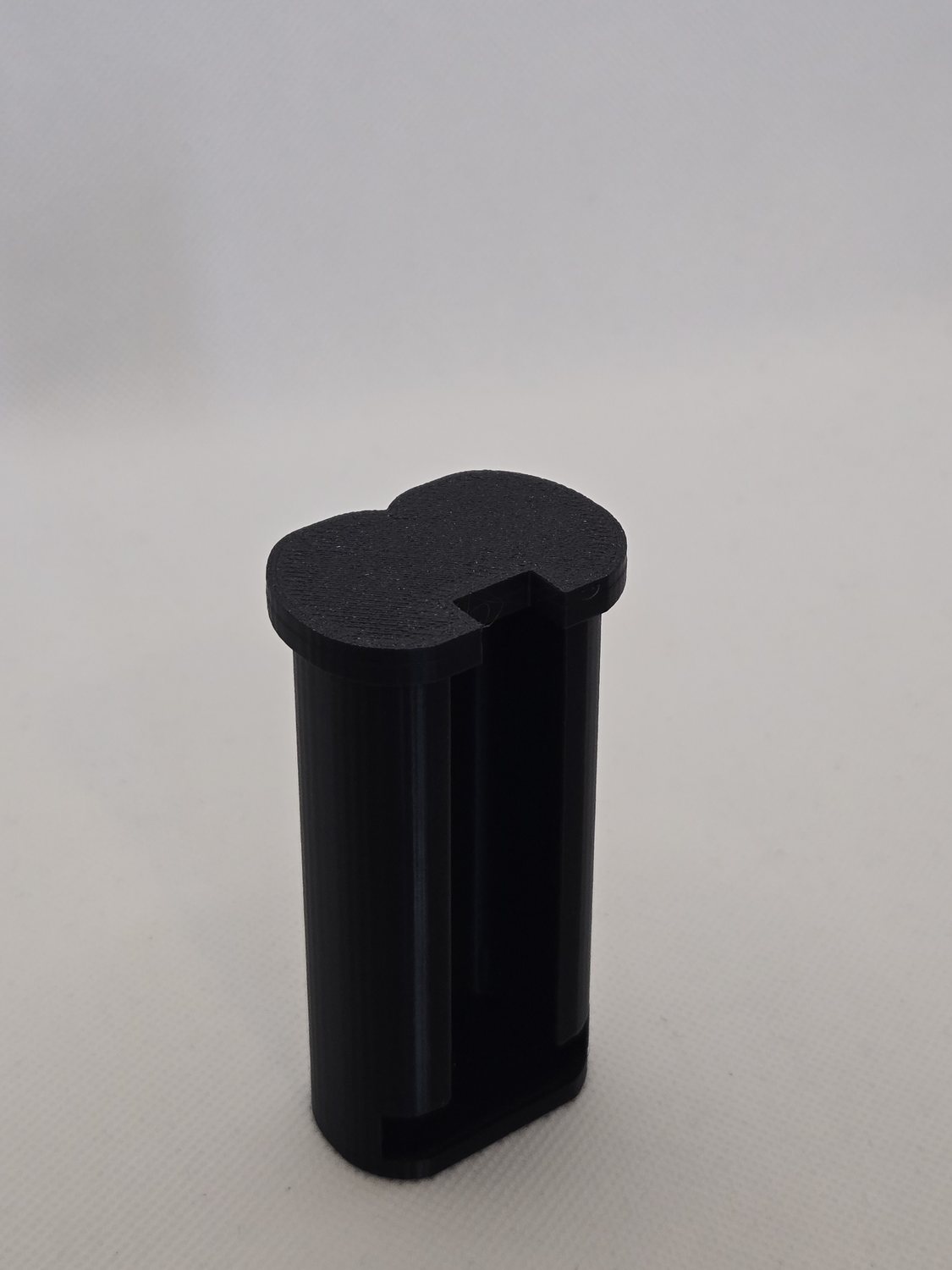 The Elephant Cover display container closed, a printed black tube with a cap