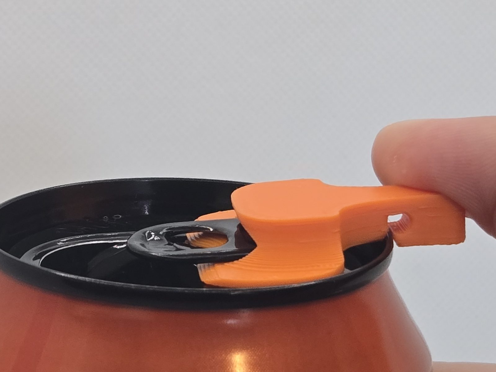 Lifting the can cover's trunk up off the tab to drink from the can